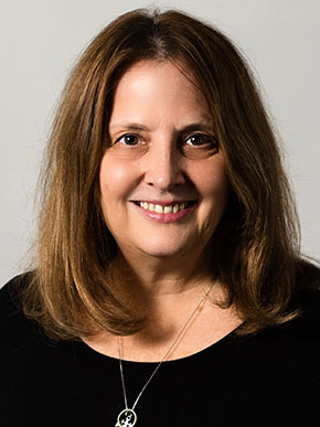 Middle-aged white woman with shoulder-length golden brown hair. She is wearing black and smiling.